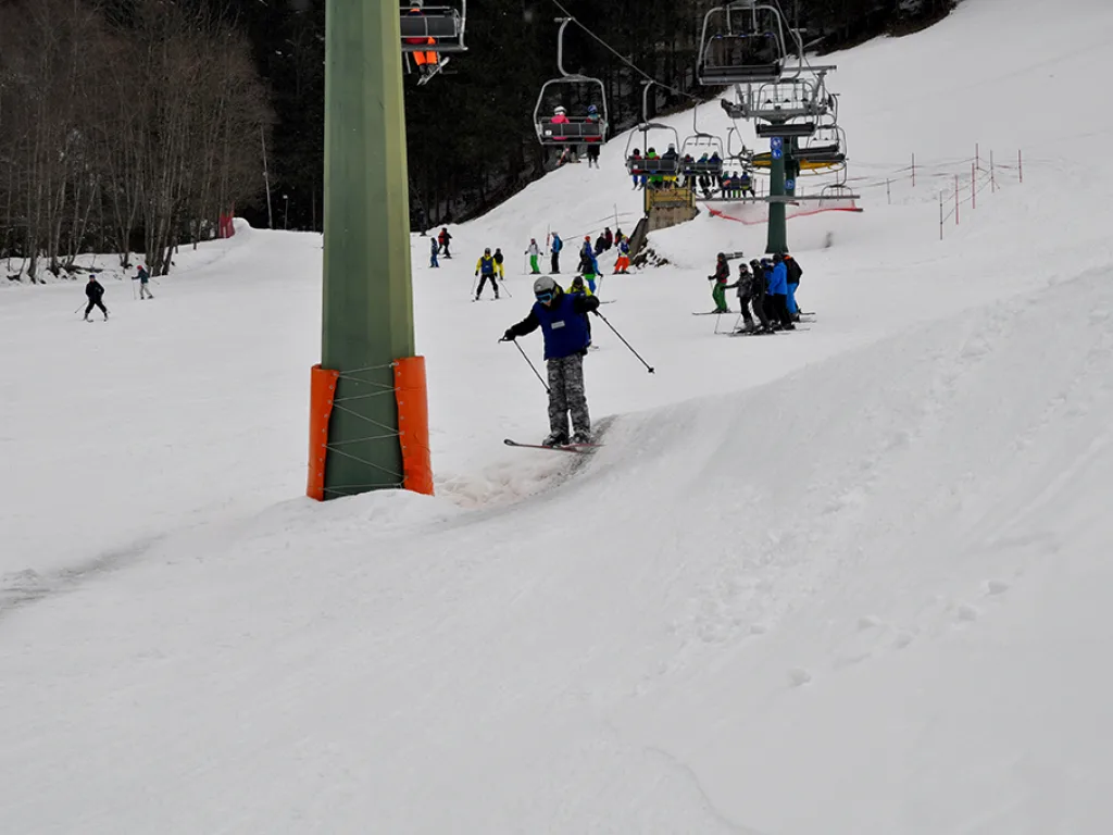 Skifahrer neben der Liftstütze auf dem Hang.
